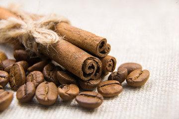 Many of roasted coffee beans and cinnamon on the tablecloth