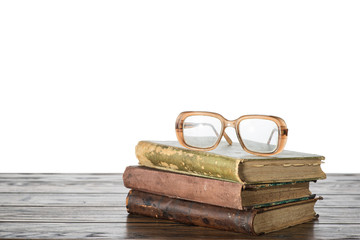 Old books and eyeglasses on a table with isolated background