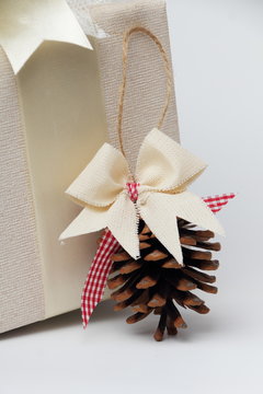 Beautifully wrapped gift with a pine cone./Beautiful gift box with packing beige paper, gold ribbon and lace. Pine cone.