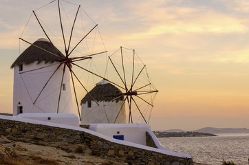      Windmills in Chora,Mykonos,Greece at sunset.Greek whitewashed architecture,a popular landmark,tourist destination on the island of winds,deep blue sky,Aegean sea. Wind mills are now decorative.  © f8grapher