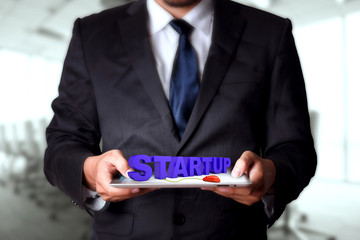 Startup text on tablet with businessman on background