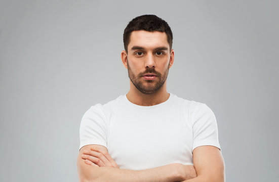 young man with crossed arms over gray background