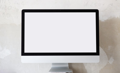 Computer-Bildschirm vor Beton-Wand und weißem Screen