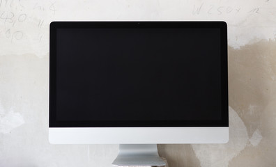 Computer-Bildschirm vor Beton-Wand und schwarzem Screen