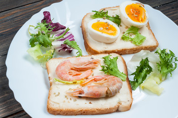 Sandwiches with shrimp, egg, basil, salad, bread on wood background. Delicious cold snacks. Vegetarian meals. Healthy eating