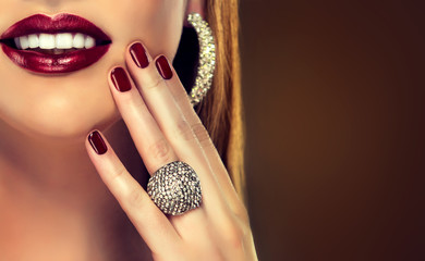 Obrazy na Szkle  Piękna dziewczyna pokazuje czarne paznokcie do manicure. makijaż i kosmetyki, piękny uśmiech z białymi zębami. Biżuteria, pierścionek i kolczyki