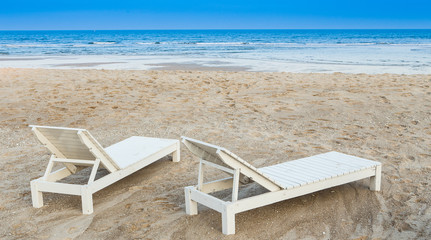 White wooden chair. Placed on the sand beach by the sea.