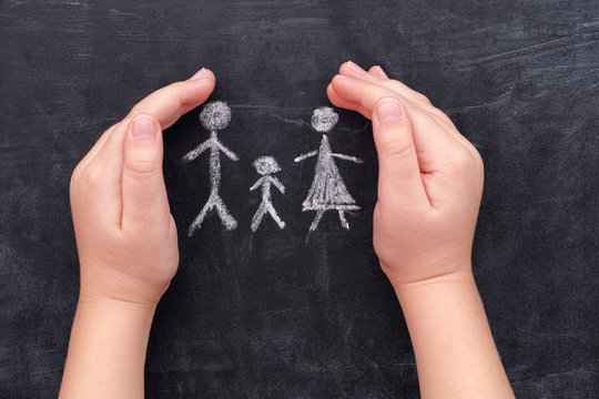 Child hands protecting family drawn on chalkboard
