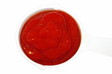 Ketchup measured out in a measuring cup on a white background

