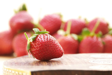 Strawberry close-up with stack of strawberries as blur background