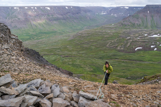 Female hiker ascends rough landscape of Iceland.