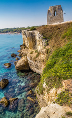 Fototapeta na wymiar Ruins of watchtower on cove on the coast of Puglia