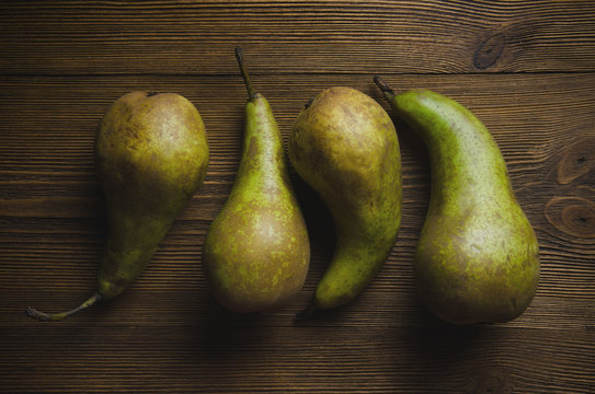 Several ripe pears lying on a wooden textural background