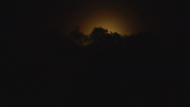 A dark clouds covers a full round moon on night sky
