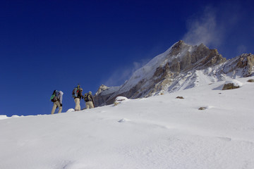 Fototapeta na wymiar A team of mountaineers going to summit with snow and wind