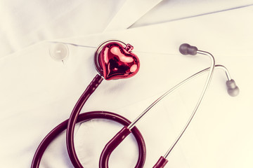 Stethoscope and decorative red heart on white doctor's overall