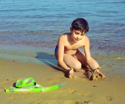 boy on the beach take sun bathing play with sand