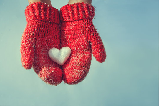 Female hands in knitted mittens with a vintage romantic red hear