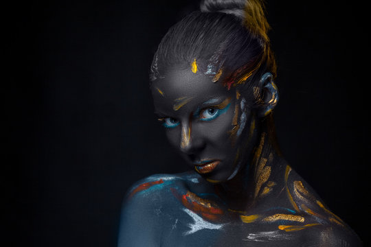 Portrait of a young woman who is posing covered with  black paint 