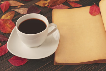 cup of coffee with a book and red autumn leaves