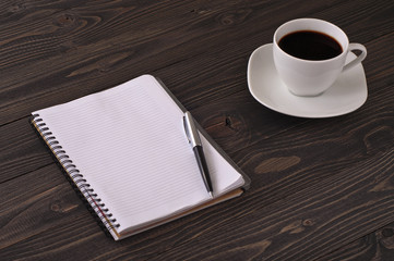 Open notebook with blank pages, pen and cup of coffee