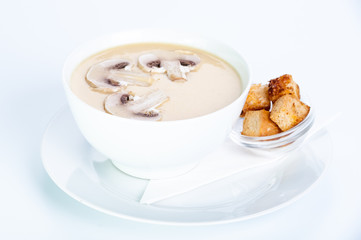 Creamy cream soup with mushrooms and croutons on a white background