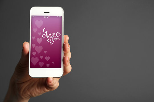 Hand holding smart phone with romantic screensaver