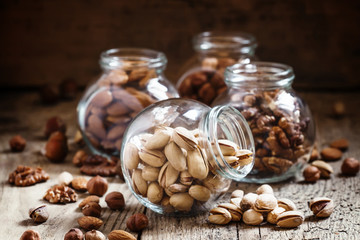 Fototapeta na wymiar Salted pistachios in a glass jar, nut mix, selective focus
