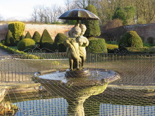 Statue fountain of little girl and boy with a puppy and an umbrella at Sewerby Park, Bridlington, East Yorkshire UK