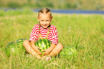 Small girl with watermelons on lawn