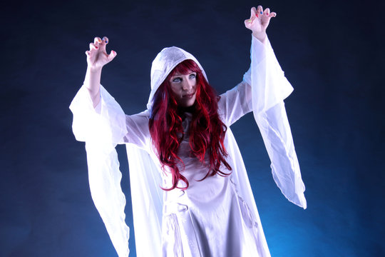 Eine Frau im Kostüm einer weißen Zauberin hebt die Hände hoch