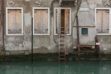 boarded-up building with ladder leading to the canal, Venice, Italy
