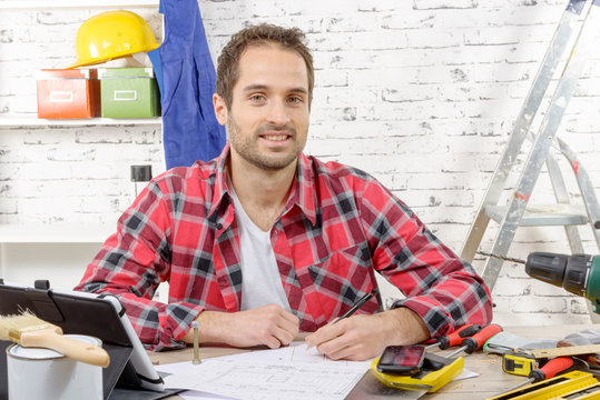 smiling carpenter sitting at the desk, in his studio