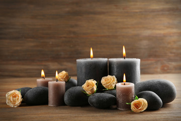 Alight wax grey candles with roses and pebbles on wooden background - relax concept