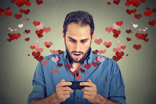Shocked man sending receiving love sms text message on mobile phone