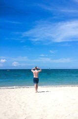 Young white man walking towards ocean