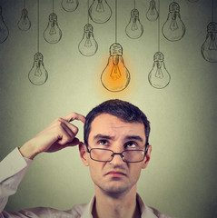 Portrait thinking man in glasses looking up with light idea bulb above head .