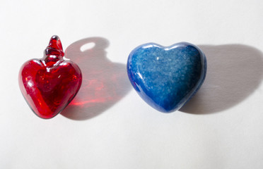 Red glass heart and blue stone heart on white background. Valentine's Day