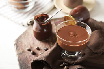 Melted chocolate on glass bowl, on wooden background