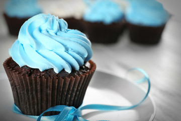 Delicious chocolate cupcake with blue cream on decorated wooden  table, close up