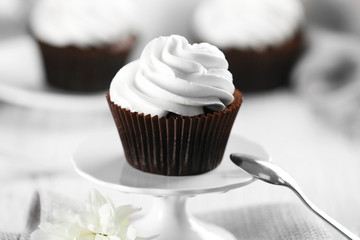 Delicious chocolate cupcake with cream on served table, close up