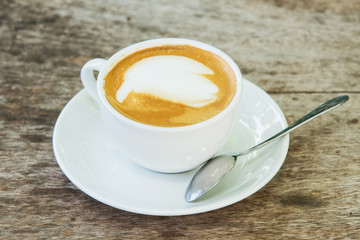 coffee with pattern in a white cup on wooden background
