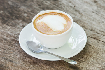 coffee with pattern in a white cup on wooden background