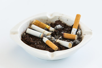 Overhead of burning cigarette in ashtray on white background