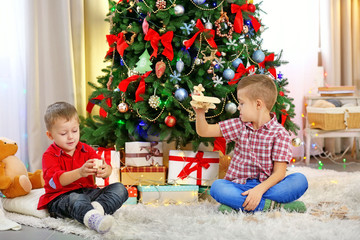 Two cute small brothers playing with wooden plane on Christmas tree background