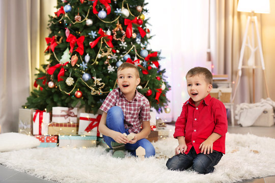 Two Cute Small Brothers Playing With Wooden Toys On Christmas Tree Background