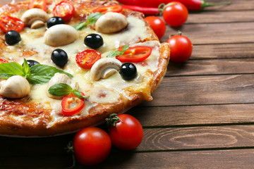 Delicious pizza and fresh vegetables on wooden background, close up
