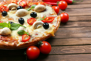 Delicious pizza and fresh vegetables on wooden background, close up