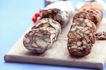 Chocolate salami on a chopping board over blue background, close up