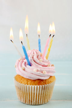 Tasty pink cupcakes decorated with candles on light background